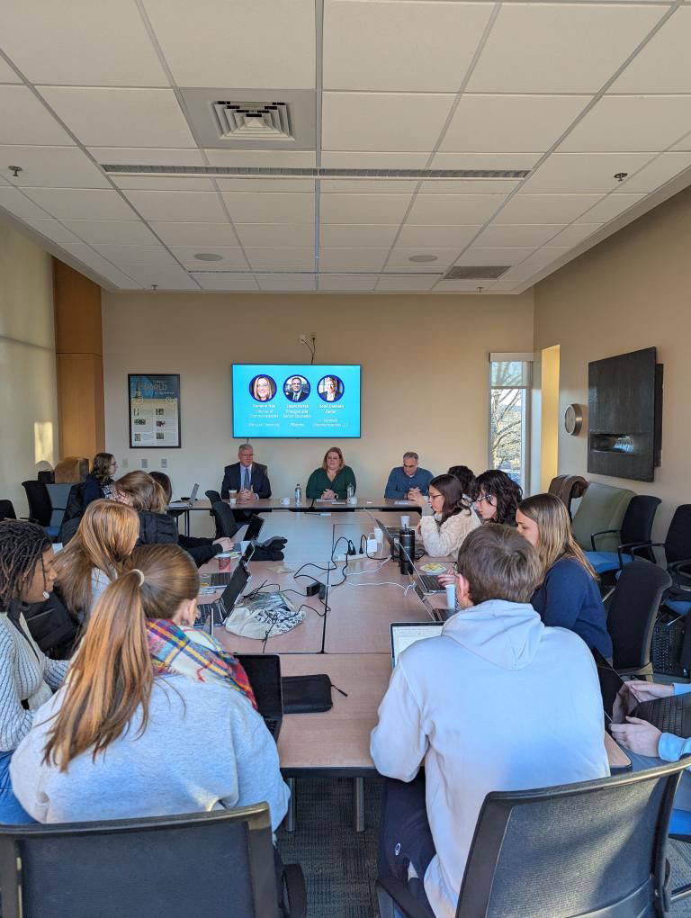 Students sitting in room looking at presentation on television