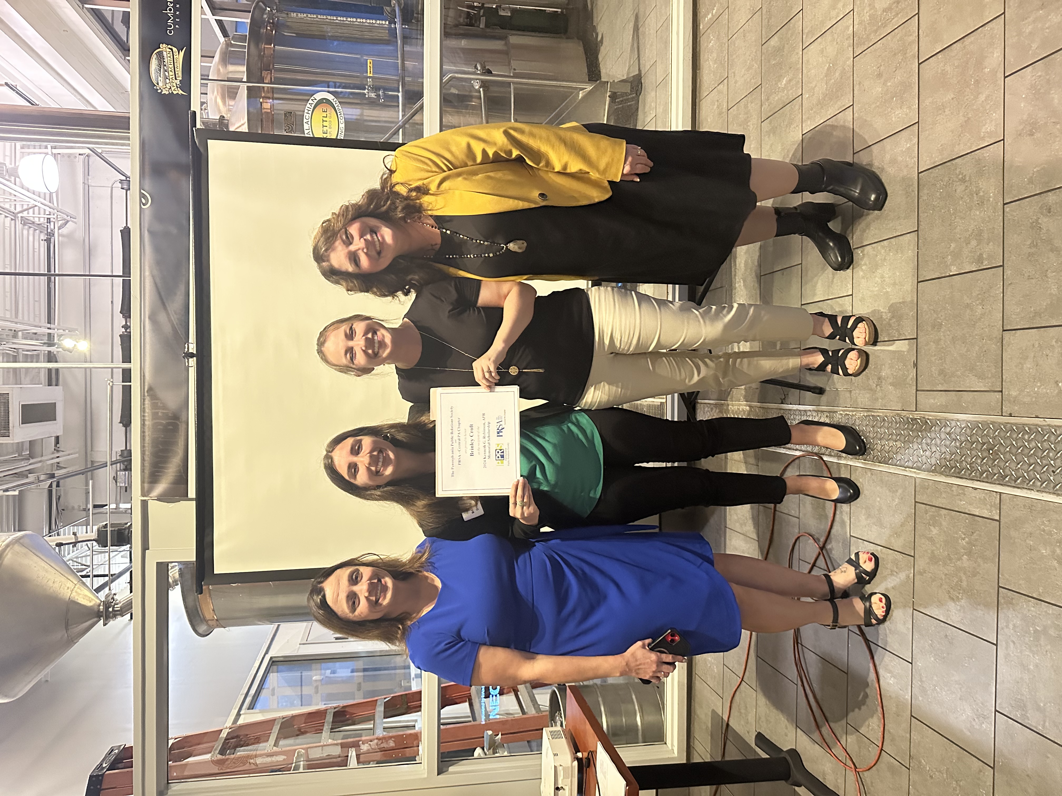 Student standing with adults presenting award