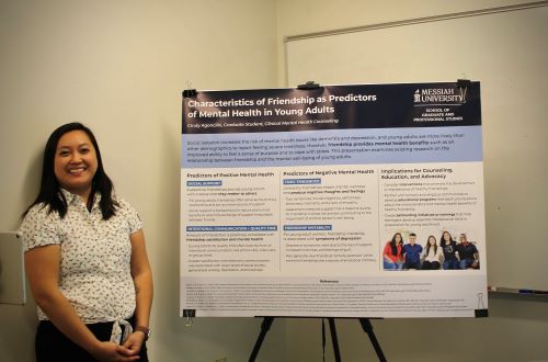 A student standing next to a poster board