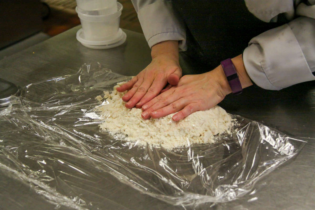 Hands pressing down on the pie dough.