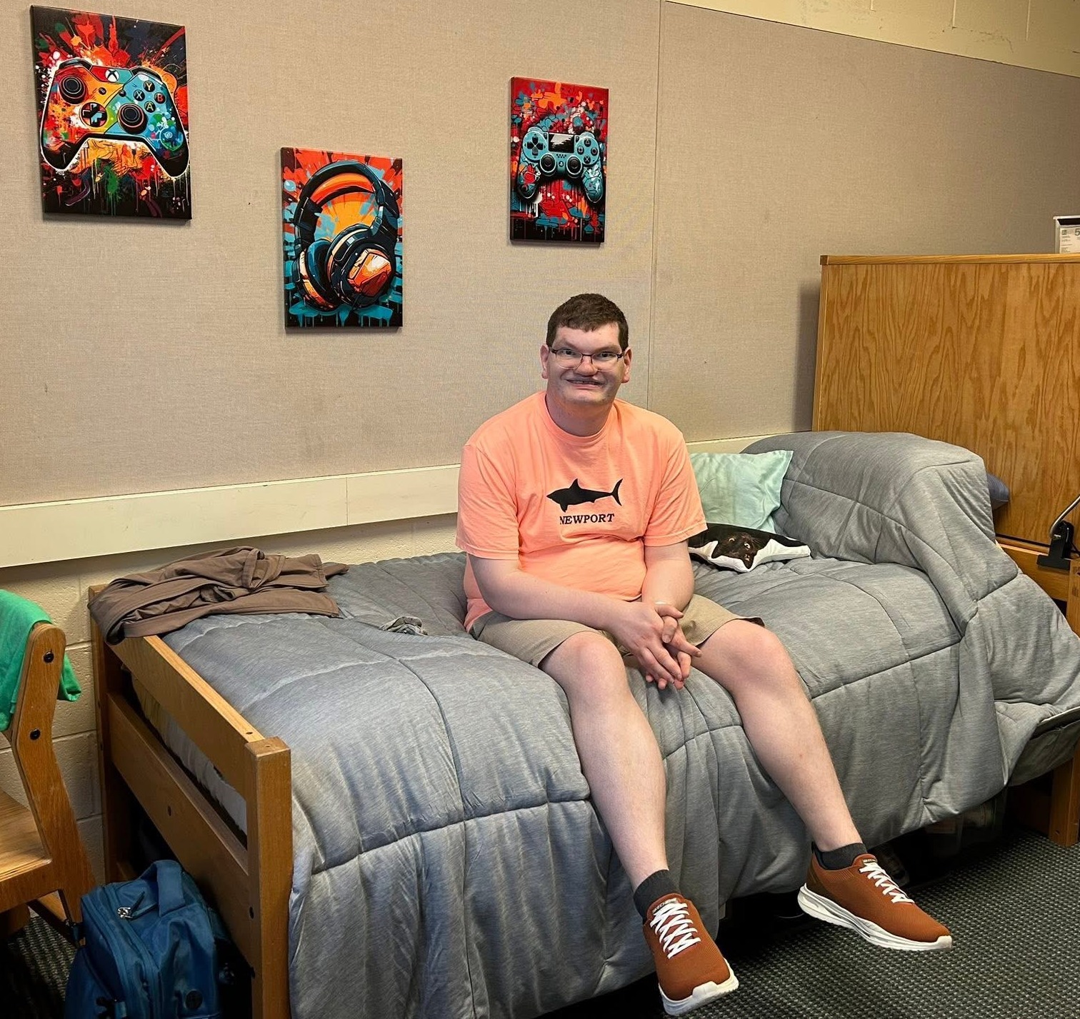 Student sitting on bed in dorm room.