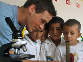 A teacher at a microscope with students